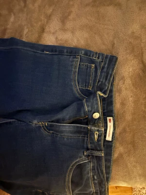 Mörkblå skinny jeans från Levi's - Säljer ett par mörkblå skinny jeans från Levi's med klassisk femficksmodell och gul kontrastsöm. Jeansen har normal midja och dragkedjegylf. Perfekta till en avslappnad streetstyle-look. Low waist