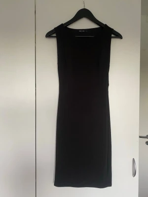 Svart ärmlös klänning från NLY ONE - En stilren svart ärmlös klänning från NLY ONE med rak passform och rund halsringning. Klänningen är lång och har en minimalistisk design som passar perfekt till olika tillfällen. Materialet känns mjukt och stretchigt. 