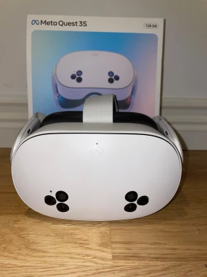 Meta Quest 3S VR-glasögon 128GB - Meta Quest 3S VR-glasögon med 128GB lagring. Snygg vit design med svarta detaljer och flera kameror på framsidan. Justerbart huvudband och bekväm passform. Perfekt för gaming och VR-upplevelser. Levereras i originalförpackning.