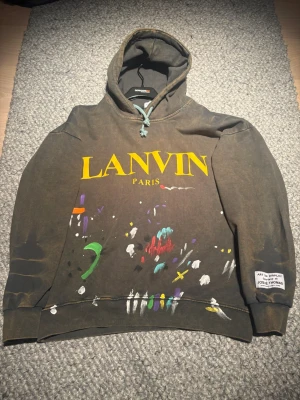 Lanvin x Gallery Dept hoodie - Unik hoodie från Lanvin x Gallery Dept i mörkbrunt med färgstänk och stor gul LANVIN PARIS-logga framtill. 