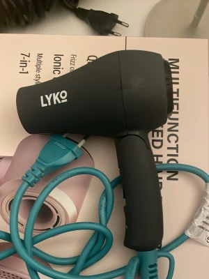 Svart hårfön från Lyko - Säljer en svart hårfön från Lyko med kompakt design och blå sladd. Perfekt för att snabbt torka håret och styla det som du vill. Hårfönen har ett modernt utseende och är enkel att använda. Passar till alla hårtyper.