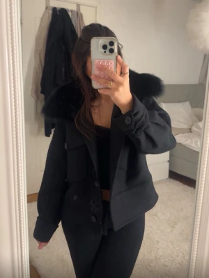 Svart pälsjacka med stor krage - Snygg svart pälsjacka med stor fluffig fuskpäls-krage. Jackan har en boxig passform, stora fickor framtill och knappar. Perfekt för kalla dagar när du vill vara varm,  den ser helt ny ut eftersom den bara använts en gång🫶🏼 