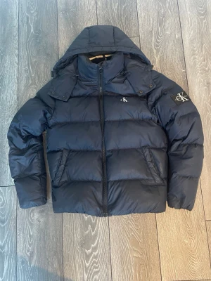 Calvin Klein jacka  - Tjena säljer min mörkblå pufferjacka från Calvin klein för att den nu är för liten. Jackan är i bra skick men har små defekter. Perfekt för kalla dagar och riktigt skön att bära. Hör av dig vid intresse eller om du har övriga funderingar 🙌