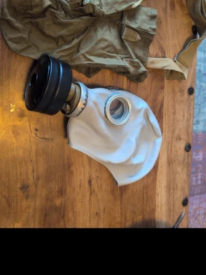 Vit gasmask med filter och väska - Klassisk replika av den ryska GP5 gasmasken med autentisk och tidstypisk design. Inspirerad av kalla krigets estetik och perfekt för samlare, cosplay, airsoft, paintball eller som en unik inredningsdetalj. En iögonfallande detalj som ger karaktär utan att ta över.  OBS: Den tål inte riktiga kemikalier, men den kan filtrera ut mindre mängder rök men det rekommenderas inte att använda den i syfte att skydda dina lungor från rök