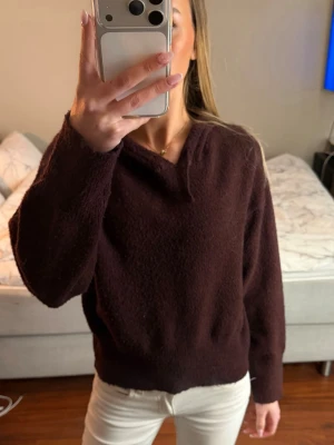 Vinröd stickad Hoodie  - Mysig vinröd stickad tröja med v-ringad hals och långa ärmar. Tröjan har en avslappnad passform och är tillverkad i ett mjukt, fluffigt material som känns skönt mot huden. Perfekt att matcha med jeans eller kjol för en trendig look. 