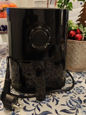 Svart airfryer från Menuett - Säljer en svart airfryer från Menuett med rund form och slät yta i plast. Den har en stor vred på framsidan för att ställa in tid upp till 30 minuter och en praktisk utdragbar korg. Perfekt för att laga mat utan olja och enkel att använda med vanlig stickkontakt.
