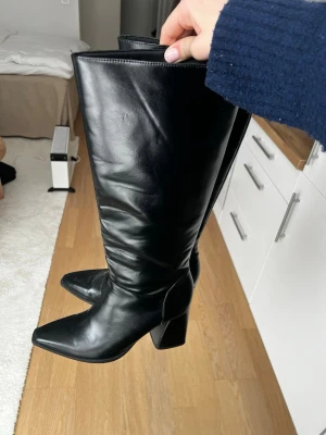 Svarta knähöga boots  - Säljer ett par svarta knähöga boots  med spetsig tå och bred klack. Från Stradivarius i strl 39, köpte för två år men kommer tyvärr inte till användning, endast använda en gång så de är i super bra skick. Skit dnyggt till en kort kjol el under ett par jeans💕💕