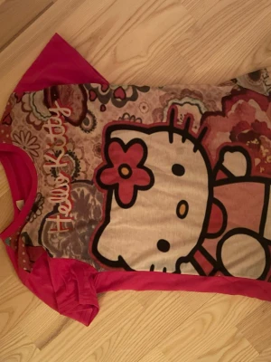 Hello Kitty tröja - En söt rosa hello Kitty tröja med blommor. Jag skulle säga att den har en lite lös passform på någon som är storlek xs/s