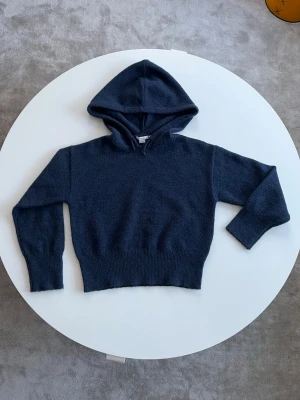 Mörkblå stickad hoodie - Skön marinblå hoodie från Gina Tricot i stickat material. Tröjan har huva med snörning och långa ärmar med ribbade muddar. Tröjan är i storlek 146/152. Den är nästan oanvänd och i jätte bra skick.🤗