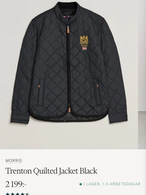 Svart quiltad vindjacka från Morris - Snygg svart quiltad höst/vårjacka från Morris med guldfärgad brodyr och brittisk flagga på bröstet. Jackan har rundad krage, dragkedja framtill och två fickor med detaljer i brunt. Perfekt för dig som gillar klassisk och stilren design.den är knappt använd så VÄLDIGT fin i skicket. Storlek XXL
