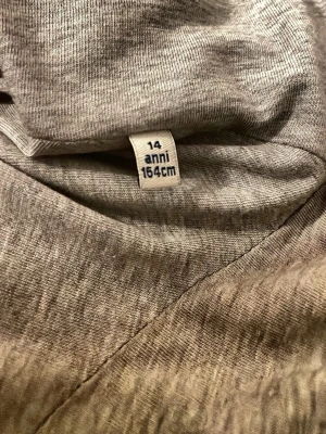 Grå jacka i polyester, 164 cm - Snygg grå jacka i mjukt polyestermaterial. Jackan har en enkel och stilren design som passar perfekt till vardags. Storlek 14 år/164 cm. Perfekt för dig som vill ha en basic jacka med skön passform.