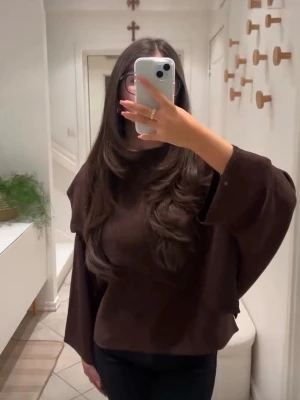 Brun oversized topp med vida ärmar - Mörkbrun topp med oversized passform och vida ärmar. Tjockare material som ger en snygg siluett och passar perfekt till jeans eller kjol. Enkel och stilren design utan synliga detaljer eller mönster. Aldrig använt, prislappen sitter till och med kvar. 