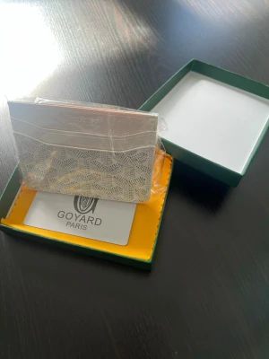 Vitt kortfodral - Snyggt vitt kortfodral med det klassiska mönstret i grått och vitt. Tillverkat i exklusivt läder med präglad logotyp upptill. Perfekt för kort och sedlar, smidig och stilren design som passar i fickan.