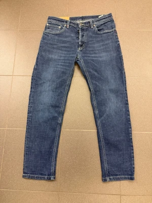 Dondup Slim fit jeans  - Säljer ett par klassiska blå jeans med rak passform från Dondup. Jeansen har fem fickor, knappgylf och detaljerade bakfickor med dekorativa sömmar. Tillverkade i slitstark denim som ger en tidlös look.