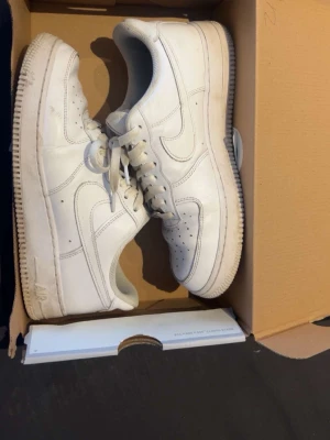 Nike Air Force 1 vita sneakers - Klassiska vita Nike Air Force 1 sneakers i lågt utförande. Skorna har en stilren design med perforerade detaljer på tån, vit sula och ikoniska Swoosh-loggan på sidan. Tillverkade i läder med snörning och vadderad häl för extra komfort pris går att diskutera!.