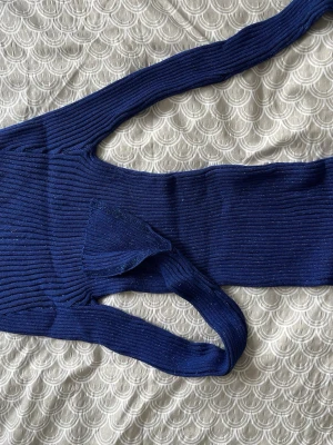 Mörkblå glitter ribbad polotröja - Tajt mörkblå glittrig ribbad polotröja med lång ärm och stretchigt material. Tröjan har en kroppsnära passform och polokrage som ger en clean och stilren look. Perfekt att bära under jackor eller som den är till jeans eller kjol.