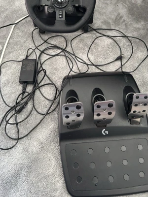 Logitech ratt och pedaler G-serien - Säljer ett Logitech racing ratt- och pedalset med svart ratt i konstläder och tre metallpedaler. Perfekt för racing- och bilspel, med realistisk känsla och många knappar för olika funktioner. Kommer med strömadapter och kablar.