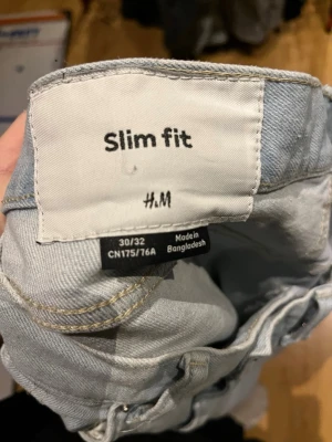 Ljusblå slim fit jeans från H&M - Säljer ett par ljusblå slim fit jeans från H&M. Jeansen har klassisk femficksmodell, raka ben och bälteshällor. Tillverkade i ett mjukt denimtyg som sitter snyggt och bekvämt. Perfekta för en avslappnad och trendig look.