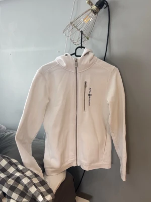 Vit hoodie från sail racing - Snygg vit hoodie från sail racing  med dragkedja framtill och en  bröstficka med zip. Klassisk huva och  logga på bröstet. Stolek 170! Pris kan diskuteras! 