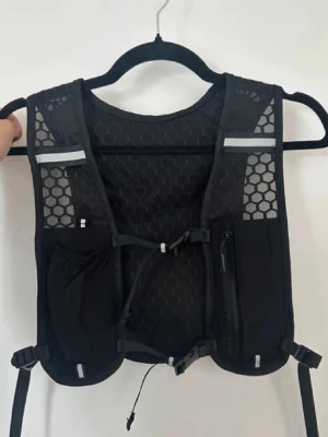 Svart löparväst med mesh och fickor - Säljer en helt ny svart löparväst. Västen har flera fickor framtill och baktill, justerbara remmar och reflekterande detaljer. Perfekt för löpning eller trailrunning när du vill bära med dig småsaker. Onesize och unisexmodell. Västen är mycket lättnavigerad andas bra. 