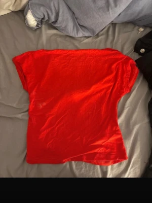 Röd topp med öppen rygg - Snygg röd topp i mjukt material med korta ärmar och en stor öppen rygg. Perfekt för dig som vill sticka ut och visa lite extra stil. Passar till många olika outfits och är enkel att matcha med både jeans och kjol.