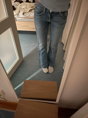 Blå bootcut jeans med broderad ficka - Säljer ett par ljusblå bootcut jeans i denim med snygg broderad bakficka och knappdetalj. Jeansen har klassisk femficksmodell och normal midja. Perfekta för dig som gillar en avslappnad men ändå trendig look. Säljer eftersom jag inte fått någon användning för dom. 