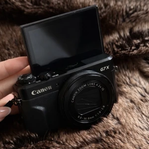 Canon G7 X mark II  - Säljer en Canon G7 X kompakt digitalkamera i svart med vinklingsbar LCD-skärm. Kameran har inbyggt zoomobjektiv (8.8-36.8mm f/1.8-2.8) och tydliga reglage för enkel hantering. Perfekt för vloggning och resor tack vare sin smidiga storlek.