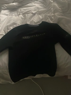 Svart Philipp Plein sweatshirt - Svart sweatshirt från Philipp Plein med silverfärgad logotyp på bröstet och en mindre logga på ärmen. Tröjan har rund halsringning och långa ärmar. Tillverkad i mjukt material för en clean och exklusiv look.