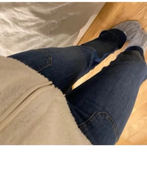 Mörkblå bootcut jeans - Säljer ett par mörkblå bootcut jeans med klassiska fickor fram och bak. Jeansen har en snygg tvätt och är tillverkade i ett mjukt denimtyg som sitter skönt. Perfekta för dig som gillar en avslappnad men ändå trendig look. 