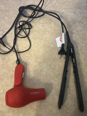 Röd hårfön och svart plattång - Säljer en röd hårfön  och en svart plattång. Hårfönen har kompakt design och vit knapp på handtaget. Plattången är smal och har sladd med EU-kontakt. Perfekt för styling av håret hemma.