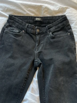 Svarta lågmidjade utsvängda jeans från ONLY - Snygga svarta  jeans från ONLY. Jeansen är i stretchigt denimtyg som sitter tajt och  skönt. Andvänt fåtal gånger storlek xs.