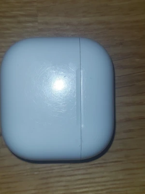 Vitt laddningsetui till Apple AirPods - Säljer ett vitt laddningsetui till Apple AirPods. Etuiet har en rundad, kompakt form och är gjort i blank plast. Perfekt för att ladda och förvara dina trådlösa hörlurar smidigt i fickan eller väskan.
