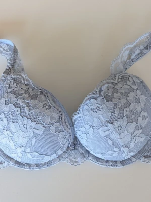 Ljusblå spets-bh med vaddering 70 A - Snygg ljusblå bh med vadderade kupor och vacker spetsdetalj över hela framsidan och axelbanden. Bh:n har bygel för extra stöd och tunna, justerbara axelband. Stlk 70 A, modell Malva från Lindex. Perfekt för dig som gillar en feminin och stilren look.