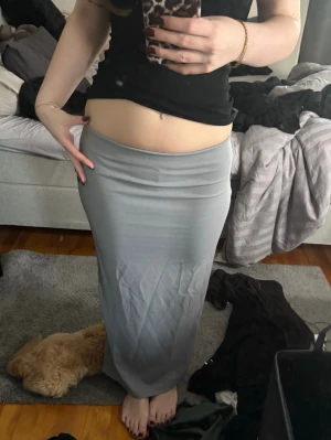 Ljusgrå långkjol med slits - Säljer en stilren ljusgrå långkjol med slits bak. Kjolen har en enkel, rak passform och är gjord i ett mjukt och stretchigt material som sitter snyggt på kroppen❤️