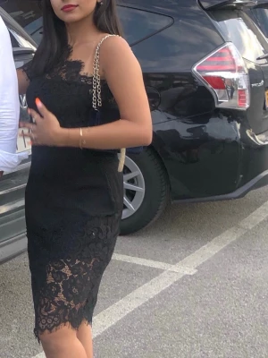 Svart spetsklänning  - En svart klänning med spetsdetaljer. Klänningen har en figurnära passform och vacker spets längs nederkanten och upptill. Använd en gång 