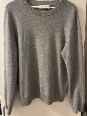 Grå cashmere-tröja A Day's March - Mjuk och stilren grå stickad tröja från A Day's March i 100% cashmere. Klassisk rund halsringning och ribbade muddar vid ärmslut och nederkant. Perfekt för dig som gillar minimalistisk och tidlös stil.