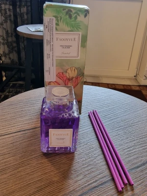 Doftspridare med stickor Lavendel - Säljer en snygg doftspridare med stickor och med lavendeldoft. Flaskan är fyrkantig och genomskinlig med lila vätska och tillhörande lila doftpinnar. Förpackningen har blommigt mönster och gröna detaljer. Perfekt för att fräscha upp rummet. Doftspridare med stickor Lavendel. 50ml rottingdoftspridare. 7 cm hög. Bredd 4 cm.