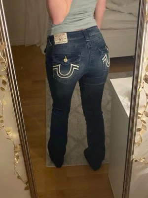 Mörkblå True Religion jeans - Säljer ett par skitsnygga jeans från True Religion i modellen Becca. Originalpris 1700❗️ Obs! Är uppsydda (visas bland bilderna) och passar mig som är ca 160cm. Midjemått: se bild Innerbenslängd: ca 75cm Perfekta för en trendig och avslappnad stil. Sparsamt använda!💕