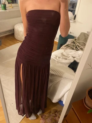 Axellös långklänning  - Plommonfärgad maxi klänning från aria cove i mesh. Den är Bandeau och har en låg midja. Klänning gen är i nyskick och endast testad med lapp kvar. Den är i storlek 34 men den är stretchiga i materialet, är själv vanligtvis 36.