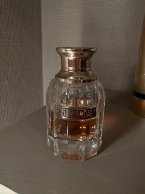 So Scandal! parfym från Jean Paul Gaultier - Lyxig parfymflaska i glas med guldigt lock från Jean Paul Gaultier, modellen So Scandal!. Flaskan har en elegant, rundad form med räfflade detaljer och en ljusrosa vätska inuti. Perfekt för dig som gillar exklusiva dofter och snygg design.