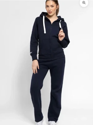 Mörkblå zip-hoodie med vita snören - Säljer en mörkblå ziphoodie från russemerch  med dragkedja framtill. xxs i storlek men passar som 146-152, bra i skick. Materialet är mjukt och bekvämt, troligtvis bomullsblandning. Säljer då den inte gått till användning. Ganska bra i skick. 