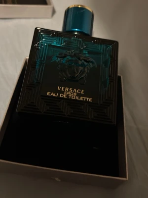 Versace Eros   - Versace Eros  i en stilren, fyrkantig flaska i mörkt turkost glas med gulddetaljer och Medusa-huvudet i relief på framsidan. Flaskan har en lyxig känsla och är perfekt för dig som gillar exklusiva dofter.