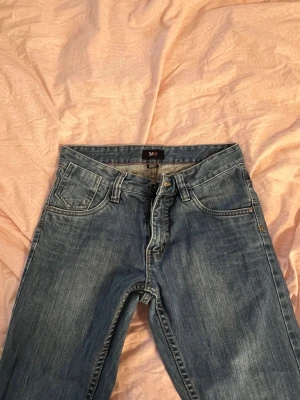 Blå jeans från SOHO New York - Klassiska blå jeans från SOHO New York med fem fickor och raka ben. Jeansen har en snygg tvättad look och detaljerade sömmar. Perfekta för en avslappnad stil och lätta att matcha med olika outfits.