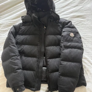 Mörkgrå Moncler Montgenevre - Moncler Montgenevre i väldigt bra skick. Enda är att cartoon har lossnat annars riktigt fin. Size 3 motsvarar medium.   Sänkt pris pga lågsäsong och ska ha ny inför nästa vinter.