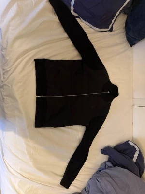 Massimo Dutti cardigan - Svart cardigan från Massimo Dutti med hel dragkedja framtill. Jackan har lång ärm, ribbade muddar och en klassisk bombermodell. Materialet är en mix av polyester och bomull vilket gör den både mjuk och lätt. Perfekt för dig som gillar en clean och stilren look.