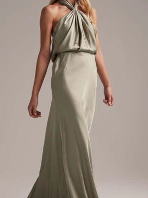 Lång beige halterneckklänning - Elegant långklänning i beige med halterneck och draperad överdel. Klänningen har en mjuk, flytande siluett och är tillverkad i ett glansigt material som ger en lyxig känsla. Perfekt för dig som vill ha en stilren och sofistikerad look.