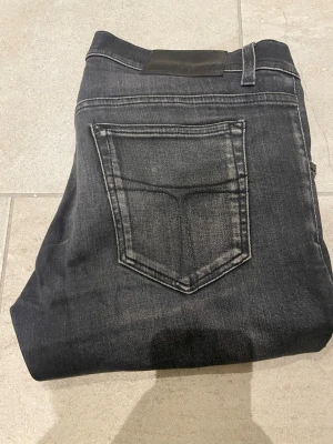 Svarta tiger of Sweden jeans - Snygga svarta  jeans med diskreta slitningar och tvättade detaljer. Klassisk femficksmodell och smal passform som sitter tight hela vägen ner. Perfekta för dig som gillar en modern och stilren look. Kan tänka mig att gå ner i pris vid snabb affär.