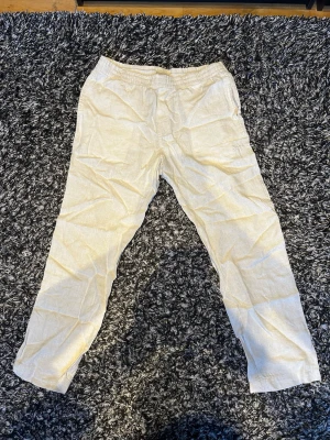 Beiga linnebyxor med rak passform - Snygga beiga linnebyxor med rak passform och klassisk look. Byxorna är tillverkade i ett lätt och luftigt linnetyg som passar perfekt för varma dagar. De har enkel design utan synliga detaljer och ger en avslappnad men stilren vibe.