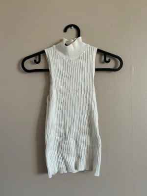 Ribbad topp med polokrage - Vit ribbad topp med turtleneck krage, från stradivarius storlek S. Liten sminkfläck vid kragen därav billigt pris (går säkert bort med vanish eller liknande har ej provat) 