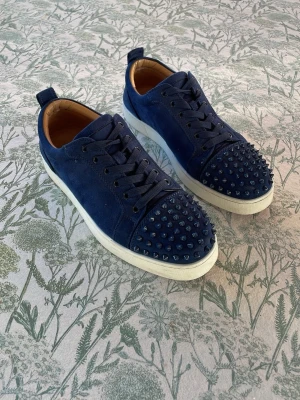 Christian loubutins  - Snygga blå sneakers med tygöverdel och coola blå nitar. Insidan är fodrad i beige och den ikoniska röda sulan.‼️INGEN BOX‼️😀jag skriver här så jag inte behöver skriva allt för mycket😁skorna e nya och är i super skick bara att sulorna inte är nya men de går och skrubba bort smutt sen🤩skorna säljs pga de är för små men de är rätt i storleken de är 43or (27,5cm) skriv vid frågor